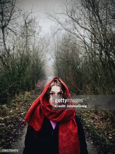 teenage girl with red scarf walking down path in misty wood - girl scarf stock pictures, royalty-free photos & images