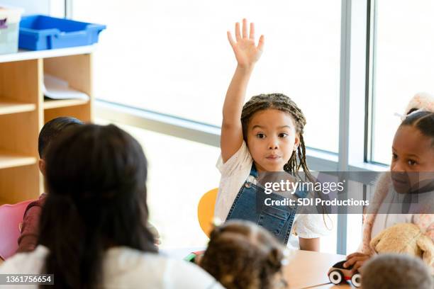 niña levanta la mano durante la clase de preescolar - 4 5 años fotografías e imágenes de stock