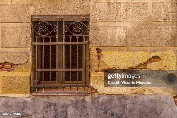 window with bars on peeling wall - sicherheitsgitter stock-fotos und bilder