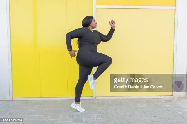 woman jumping on yellow background - fat burning stock pictures, royalty-free photos & images