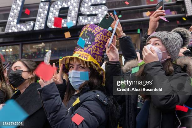 Women wearing masks react and cheer as confetti is released from the Hard Rock Cafe marquee during a ‘confetti test’ ahead of New Year’s Eve in Times...