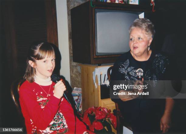 grandmother and granddaughter singing karaoke, vintage 1990s christmas photograph - child photos stock pictures, royalty-free photos & images