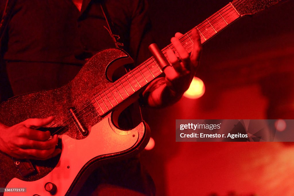 Detail of man playing guitar on stage with a silde