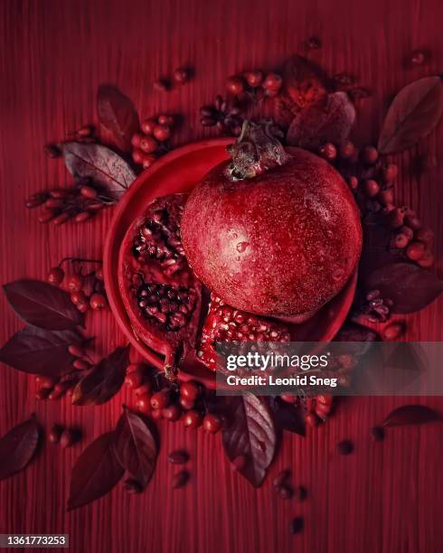 still life top view in red tones with pomegranate and autumn leaves and berries closeup. selective focus - pomegranate stock pictures, royalty-free photos & images