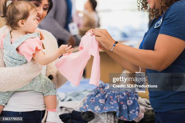 maman regarde des vêtements mignons pour bébé à la collecte de vêtements - vêtement-de-bébé photos et images de collection
