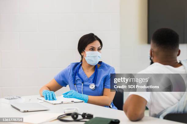 female nurse listens to patient before administering vaccine - gratis stock pictures, royalty-free photos & images