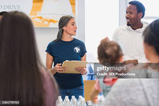 couple consults each other during volunteer event - non profit organization stock pictures, royalty-free photos & images