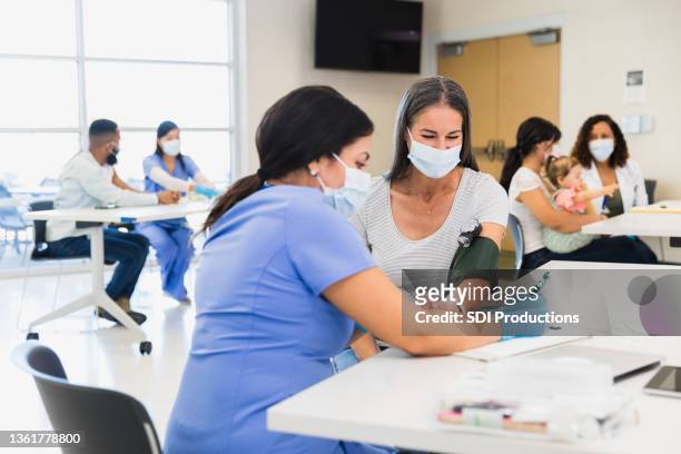 healthcare professionals see patients at busy clinic - family health club stock pictures, royalty-free photos & images
