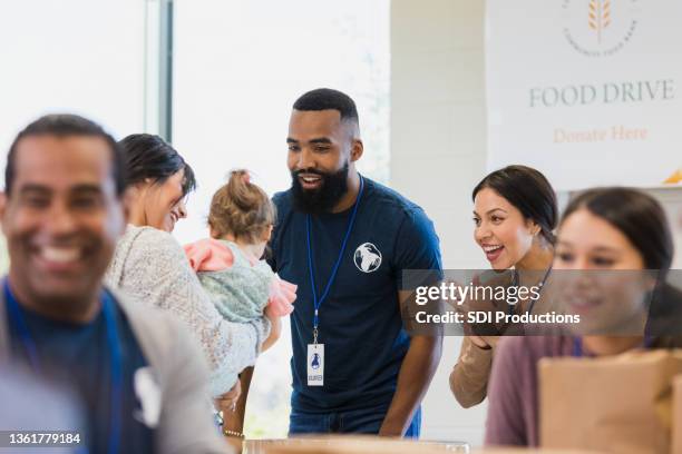 friendly volunteers talk with young mom and her baby - father and children volunteering imagens e fotografias de stock