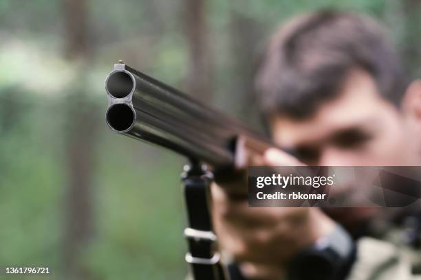 hunter shooting a double barreled shotgun close-up. aiming while hunting - hitman stock pictures, royalty-free photos & images