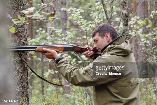 hunting in the forest on a summer day. young hunter taking aim at game - shotgun stock pictures, royalty-free photos & images