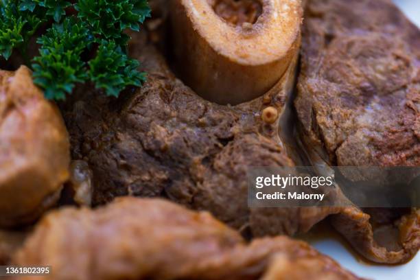 ossobuco. close-up of meat and garnish on a plate. - osso bucco stock-fotos und bilder