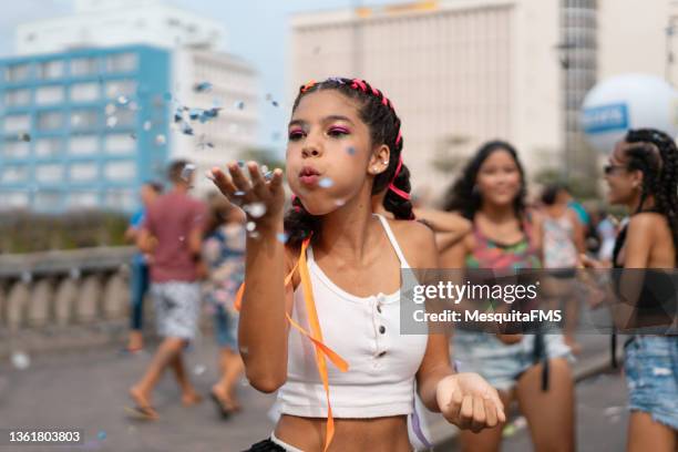 young woman blowing confetti at street carnival party - national girl child day stock pictures, royalty-free photos & images