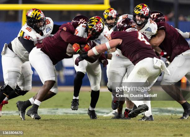 Roman Hemby of the Maryland Terrapins carries the ball and is stopped by Norell Pollard and Dax Hollifield of the Virginia Tech Hokies during the...