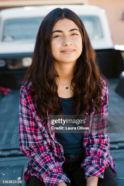 young teenage girl sits on the back of a pick-up truck at her home - girl with brown hair stock pictures, royalty-free photos & images