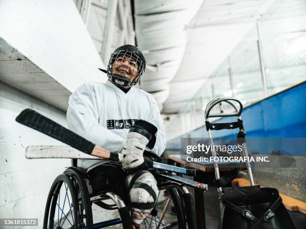 mature disabled latin woman getting ready to play sledge hockey - hockey gear stock pictures, royalty-free photos & images