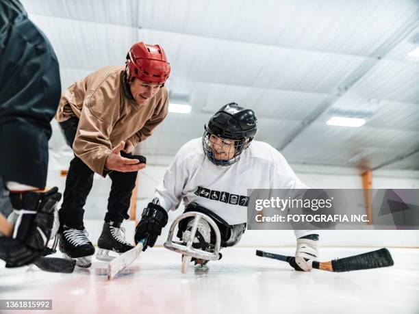 mujer latina discapacitada madura, su pareja y entrenadora practicando hockey en trineo - mens ice hockey fotografías e imágenes de stock