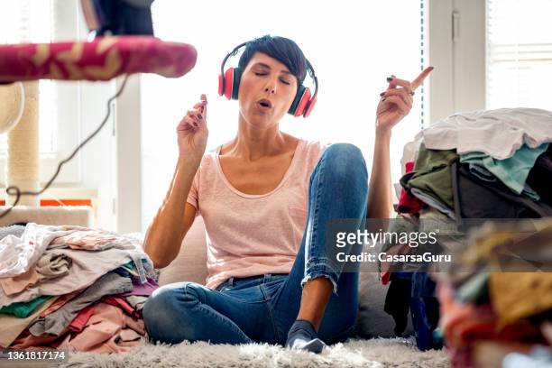 woman relaxing by listening to music and singing - ironing board imagens e fotografias de stock