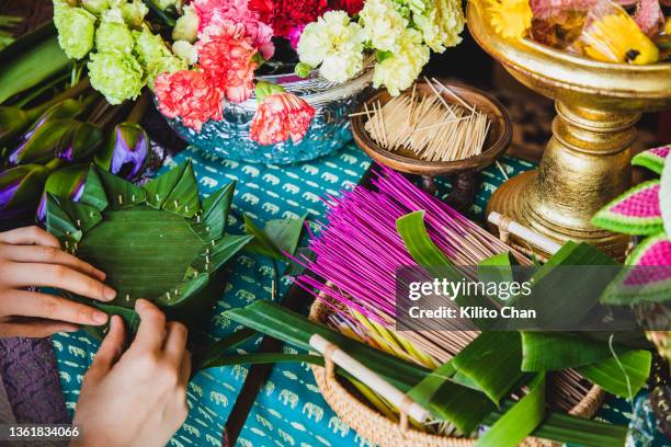 making krathong for loi krathong festival (water lantern for lantern festival of thailand) with fresh flowers, banana leaves, candle and incense) - orchids of asia - fotografias e filmes do acervo