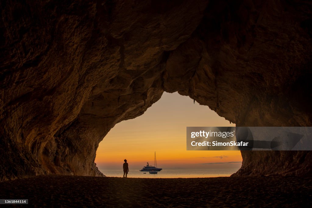 Man on the beach at Cala Luna cave at sunset, Sardinia, Italy.