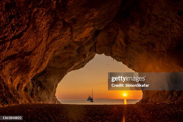 cala luna cave at sunset with sailing boats in background, sardinia, italy. - sardenha imagens e fotografias de stock