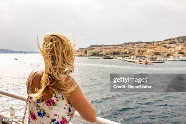 mujer rubia mirando un pequeño pueblo desde el crucero, isla de la maddalena, cerdeña, italia. - cruise fotografías e imágenes de stock