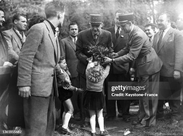 UNe petite fille offre un bouquet de muguet au Général de Gaulle lors de la grande manifestation organisée par le R.P.F. Au bois de Boulogne, le 01...