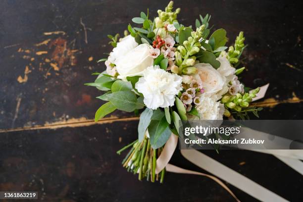 beautiful wedding bouquet on a wooden table, close-up. wedding bouquet of different flowers and green leaves, tied with a satin ribbon. wedding theme. - close up of flower bouquet stock-fotos und bilder