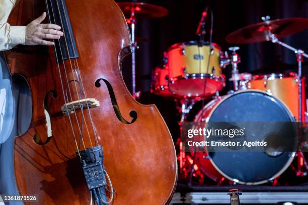 detail of man playing double bass on stage with a drum kit at background - double bass stock pictures, royalty-free photos & images