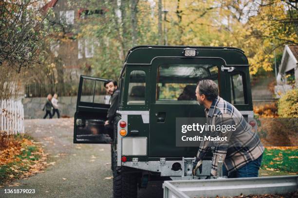 father talking with son sitting in sports utility vehicle - reversing stock pictures, royalty-free photos & images