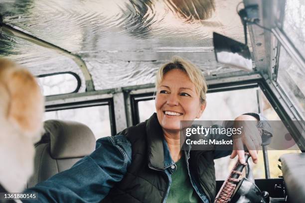 smiling woman looking away while sitting in sports utility vehicle - 4x4 stockfoto's en -beelden