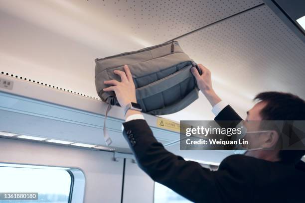 asian man putting luggage on the train rack - luggage rack stock pictures, royalty-free photos & images