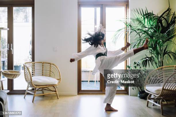 ambitious girl practicing karate in living room - karateka stock-fotos und bilder