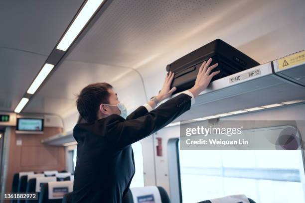 asian man put suitcase on train luggage rack - luggage rack bildbanksfoton och bilder