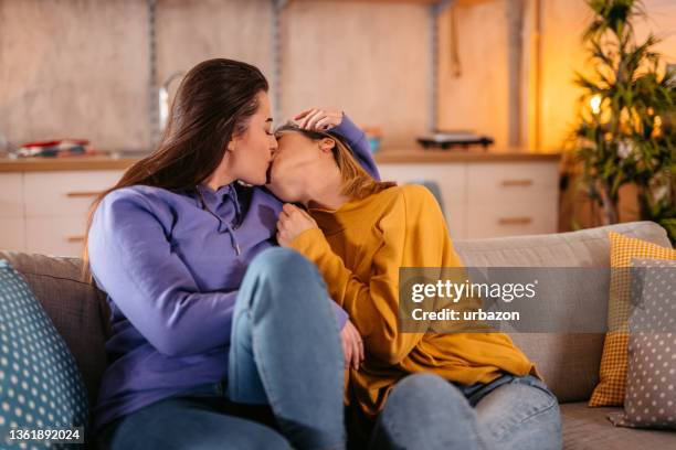 young lesbian couple kissing on sofa - images of lesbians kissing stock pictures, royalty-free photos & images