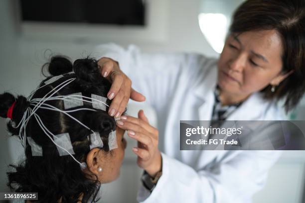 arzt platziert elektroden auf dem kopf des patienten für eine polysomnographie (schlafstudie) - neurowissenschaften stock-fotos und bilder
