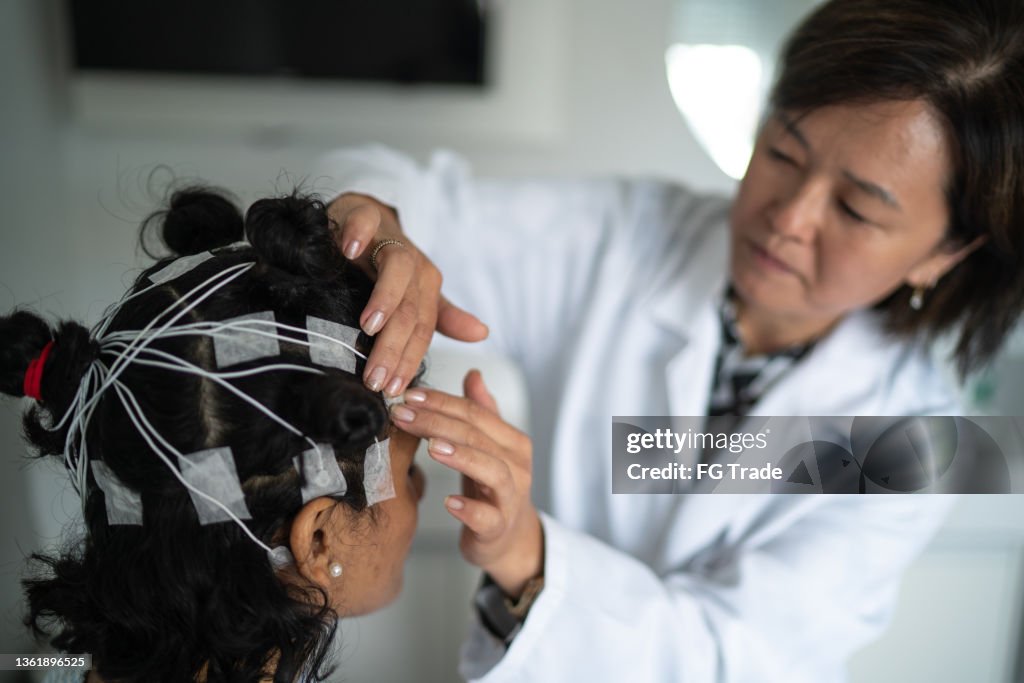 Doctor placing electrodes on patient's head for a polysomnography (sleep study)