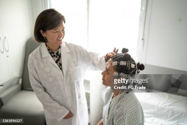 ポリソムノグラフィーのために患者の頭に話を置く医師(睡眠研究) - 神経科医 ストックフォトと画像