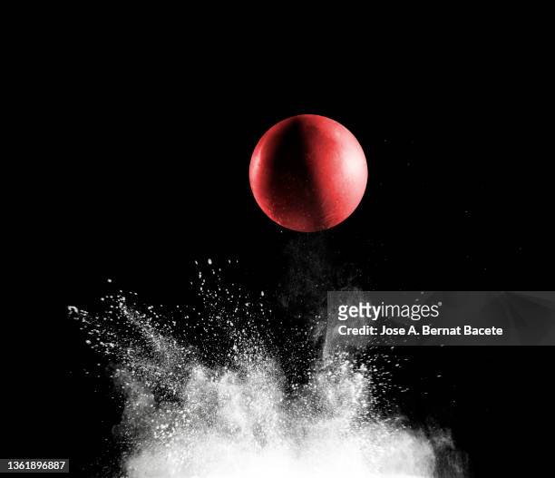 impact and rebound of a toy ball on a surface of land and powder on a black background - bouncing ball stockfoto's en -beelden