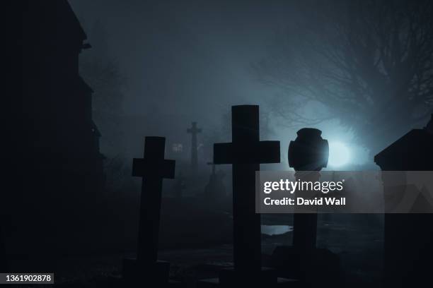a spooky graveyard. with graves silhouetted on a scary, foggy winters night - david cruz fotografías e imágenes de stock