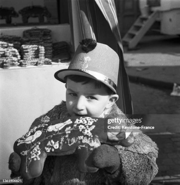 Un enfant mange du pain d'épice sur la foire du trône, le 05 mars 1951.