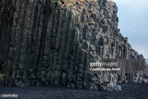 stack of basalt columns by halsanefshellir cave on reynisfjara black sand beach in iceland - lava stone stock pictures, royalty-free photos & images