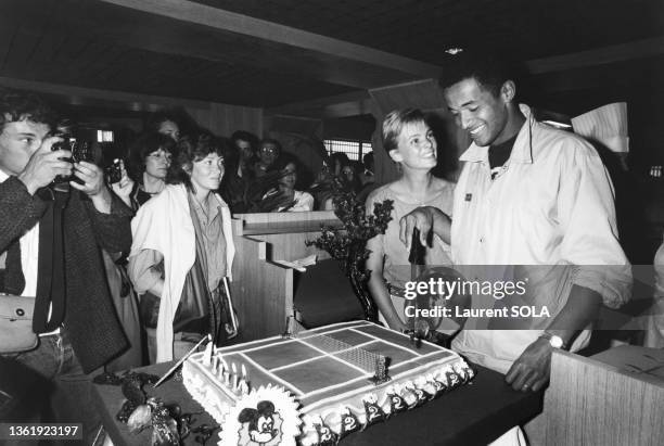 Yannick Noah et son épouse Cecilia coupe un gateau pour le lancement d'une bande dessinée consacré au tennisman à Paris le 3 mai 1984