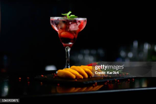 red strawberry cocktail drink with spices, pepper and basil on a table with apettizers - selective focus - cachaça stock pictures, royalty-free photos & images