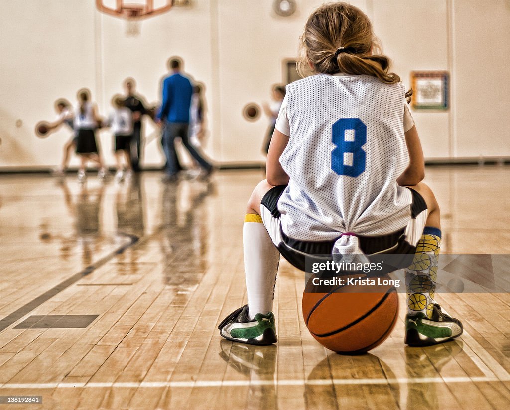 Girl sitting on basketball