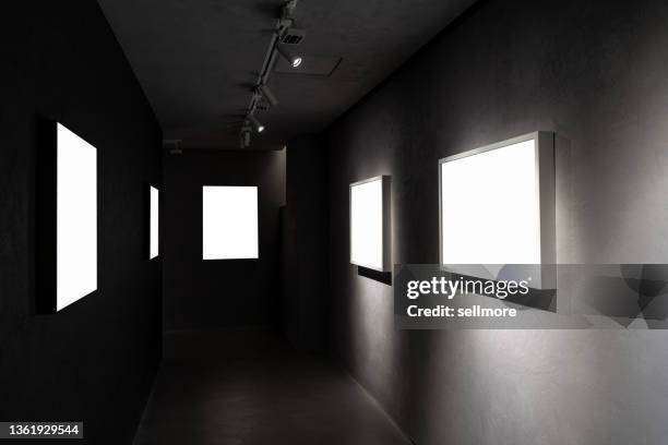 row of picture frames on the wall in the corridor of the dark room - exposition wall ストックフォトと画像