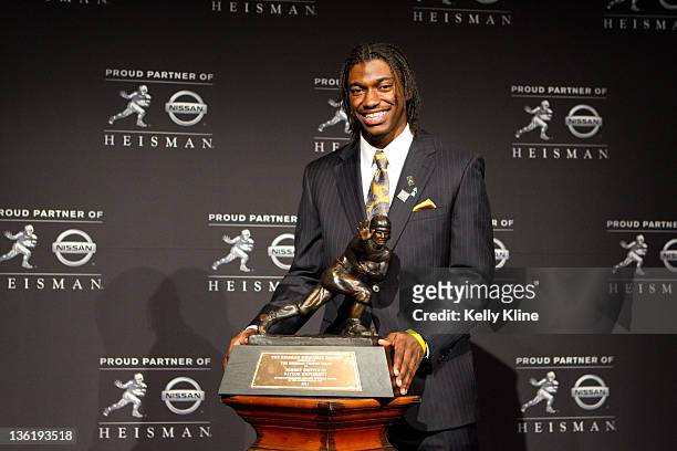 Quarterback Robert Griffin III of the Baylor Bears poses with the trophy at a press conference after being named the 77th Heisman Memorial Trophy...