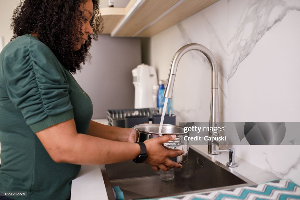 Woman filling an pan with water