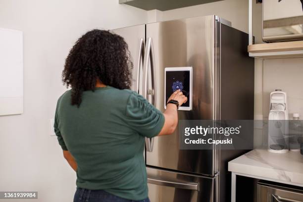 young woman checking information from smart fridge - iot stockfoto's en -beelden
