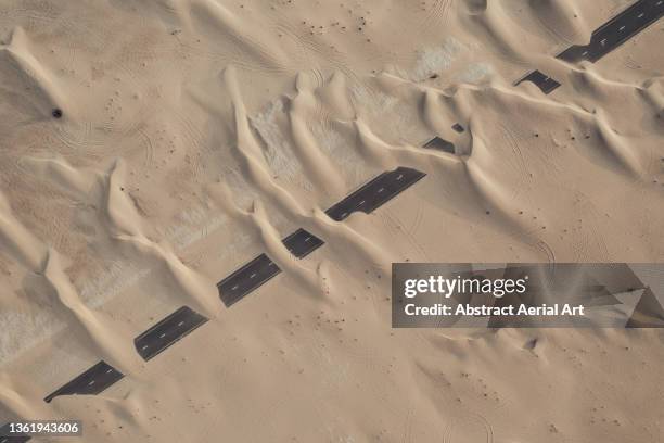 sand dunes covering an abandoned highway in the desert, dubai, united arab emirates - climate change aerial stock pictures, royalty-free photos & images